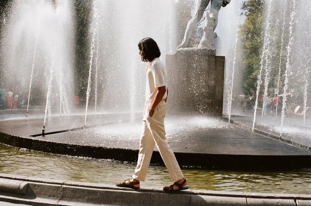 Person walking near a fountain with a statue