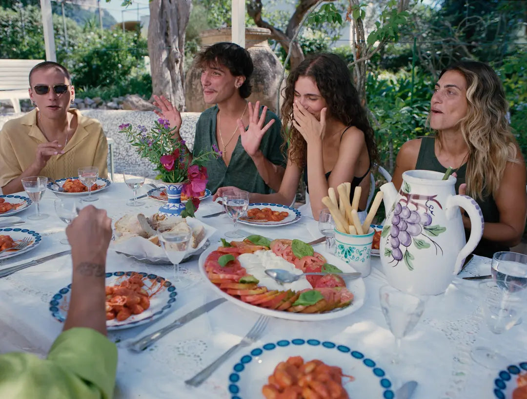 Group of people sitting around a table with food, outdoors